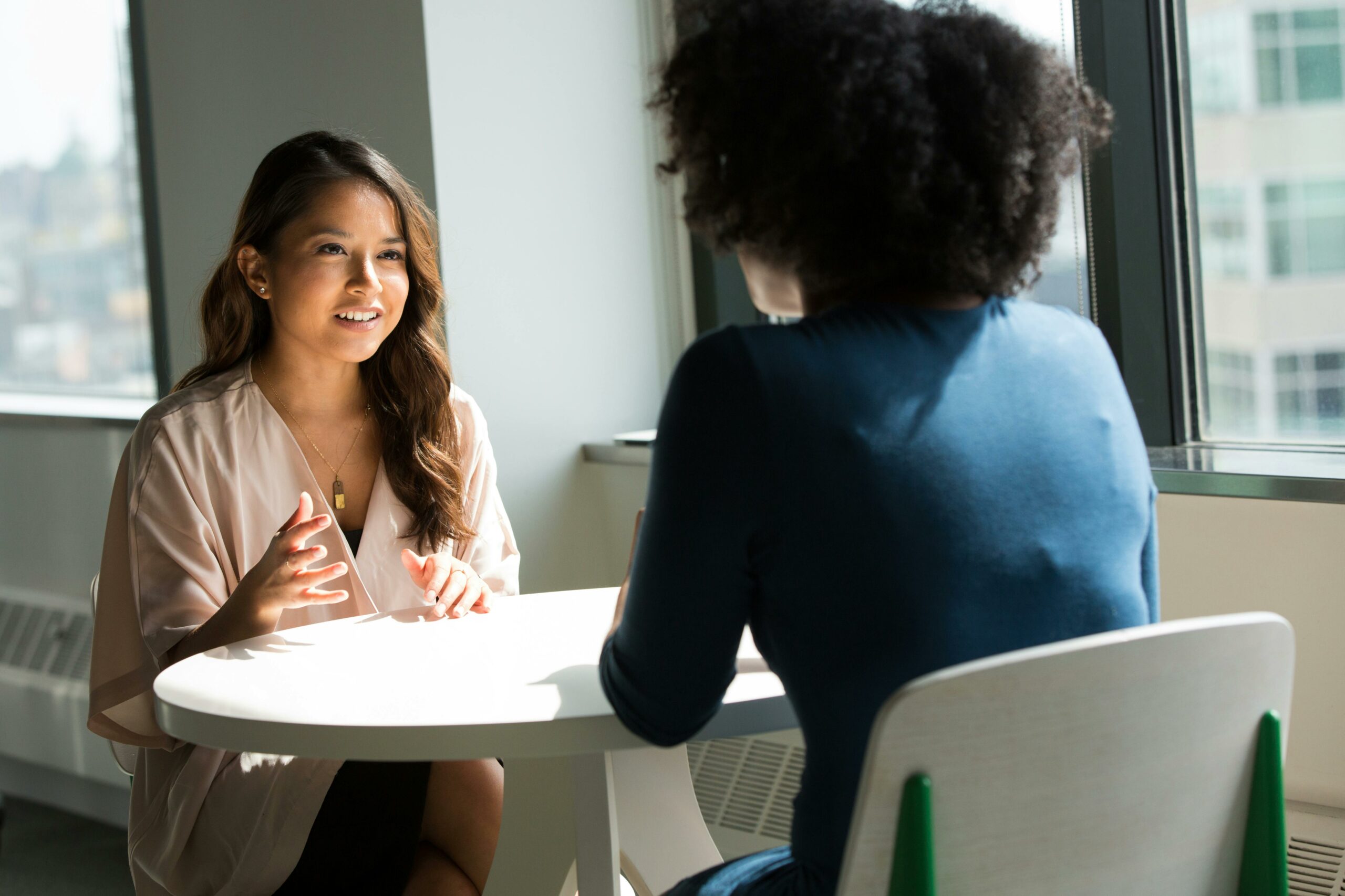 Zwei Frauen sitzen an einem Tisch und unterhalten sich